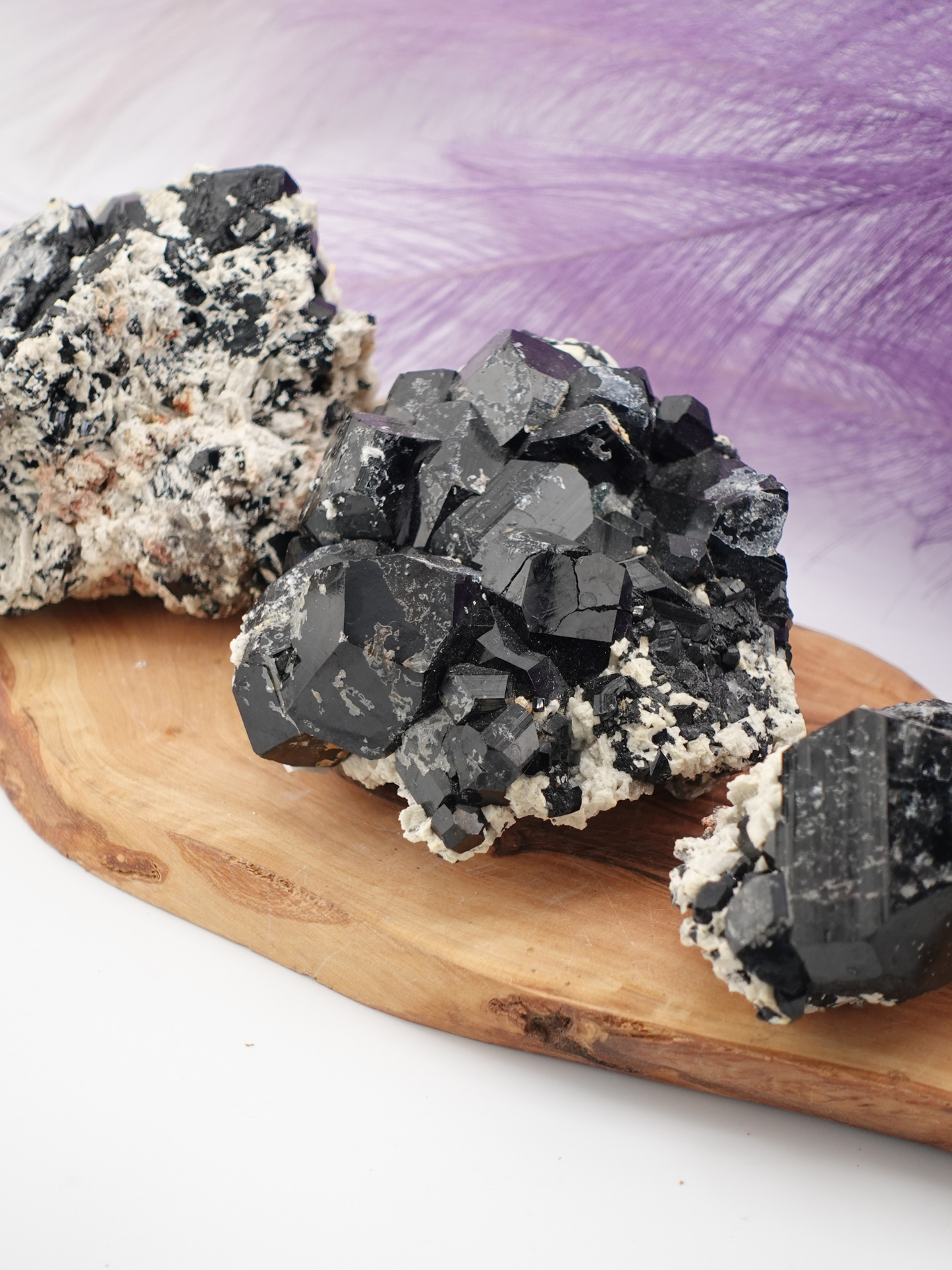 Three specimen of black tourmaline, smoky quartz, and hyalite displayed on a wooden slab.