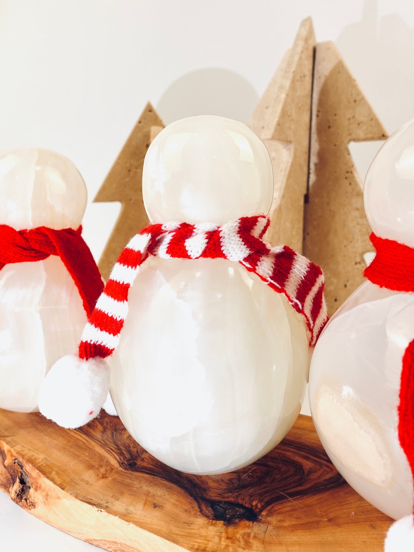 Snowman figurines with red and white striped scarves on a wooden surface