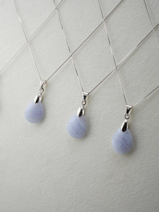 Three Blue Lace Agate pendants on a white velvet display stand