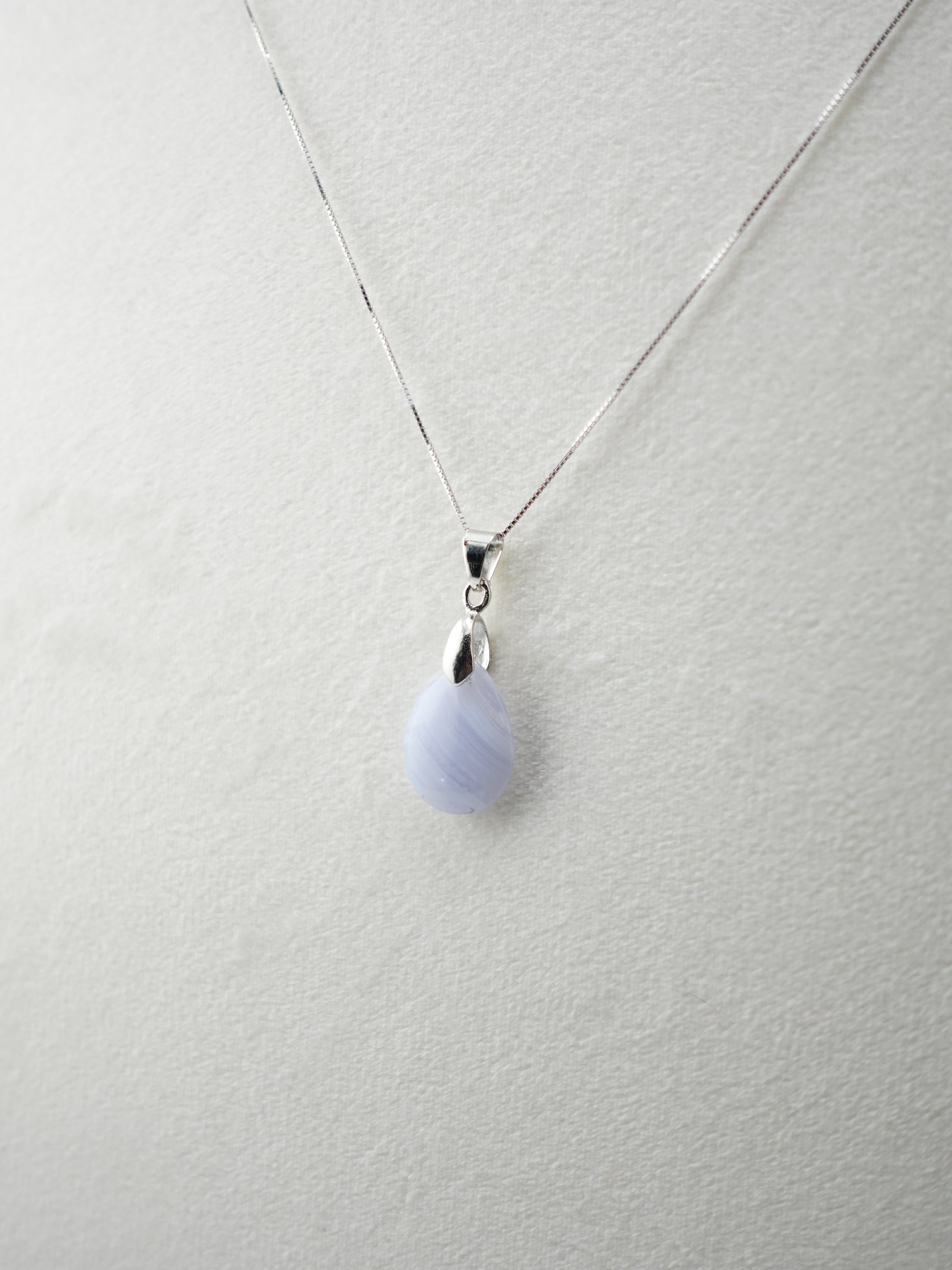 One Blue Lace Agate pendant on white velvet display stand