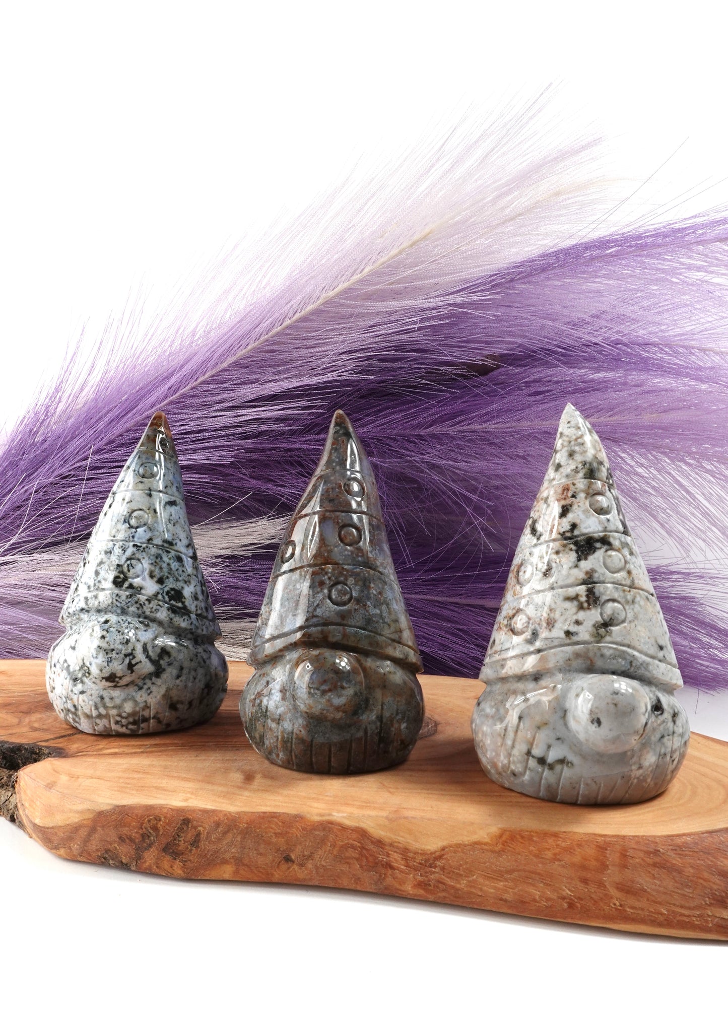 Three sea jasper gnomes on a wooden display stand