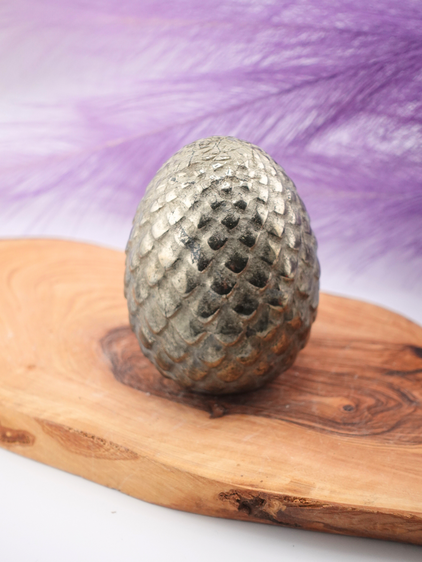 Golden colored pyrite dragon scaled egg on a wooden display stand