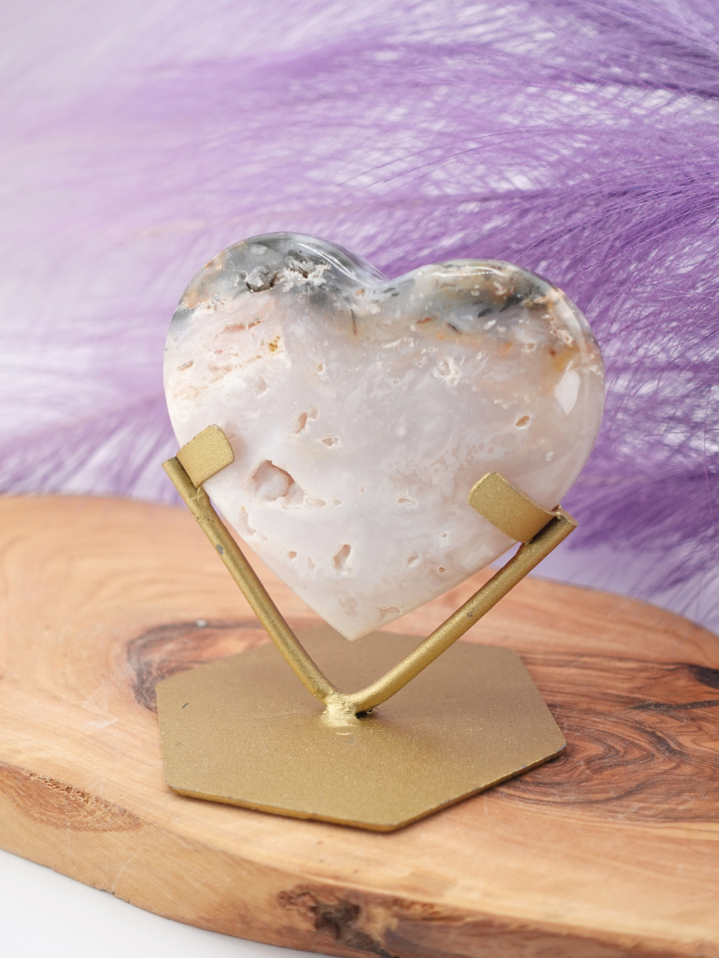 Rainbow plume agate heart on gold stand displayed on wooden stand