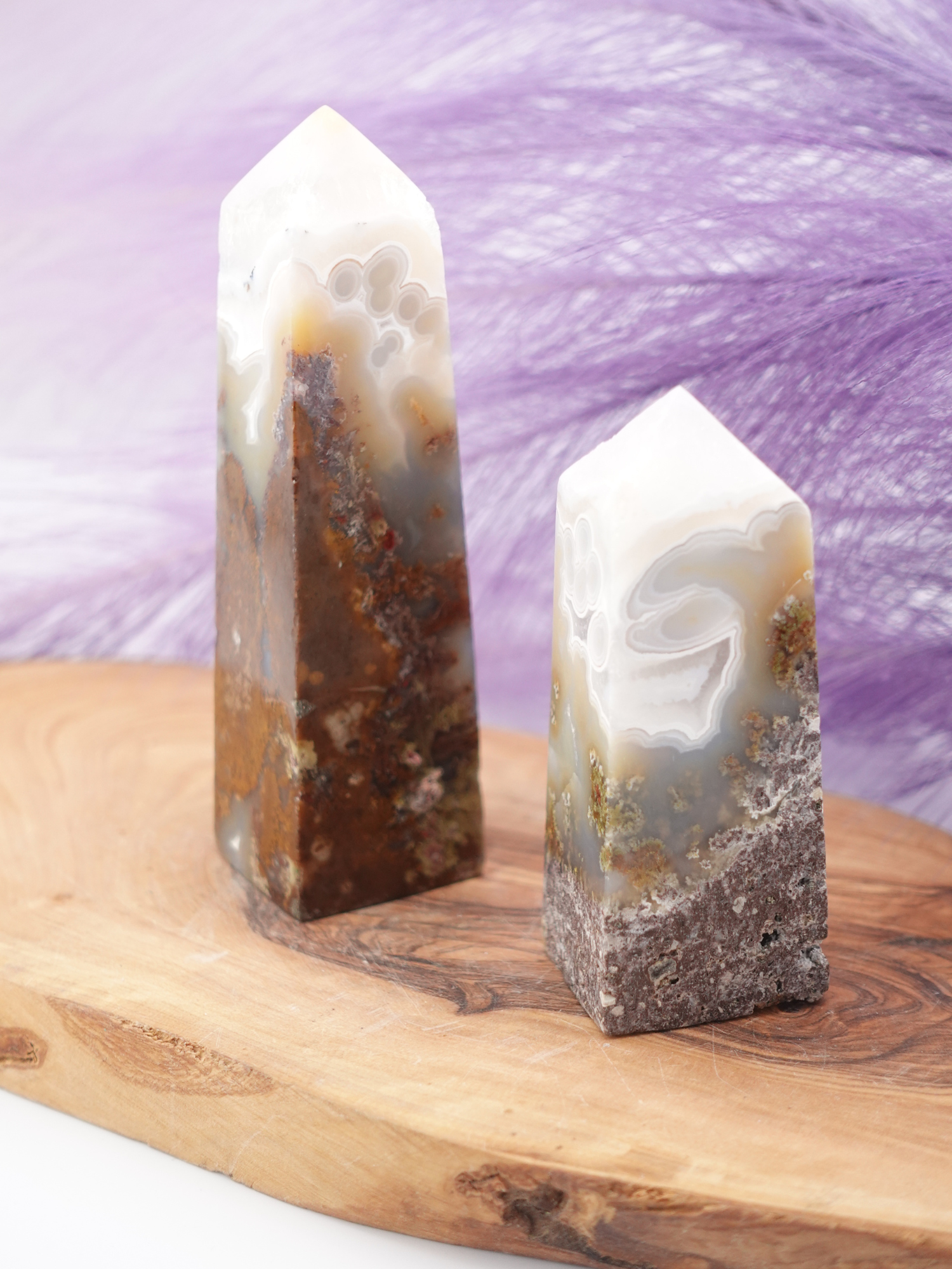 Two scenic moss agate towers on wooden display stand
