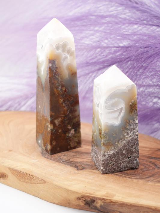 Two scenic moss agate towers on wooden display stand