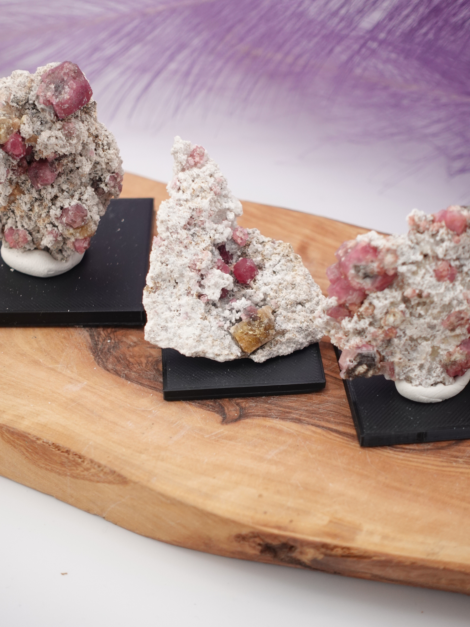 Three Raspberry Garnet Specimens on square, black stands; on wooden display stand