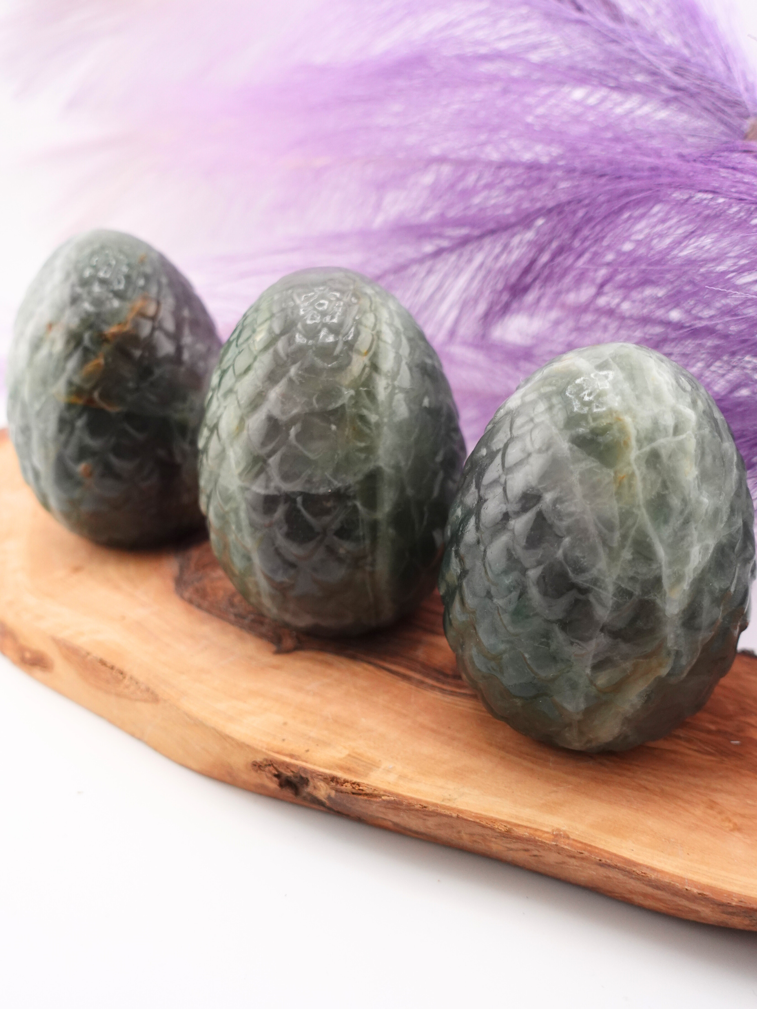 Three Fluorite dragon scaled eggs on wooden display stand