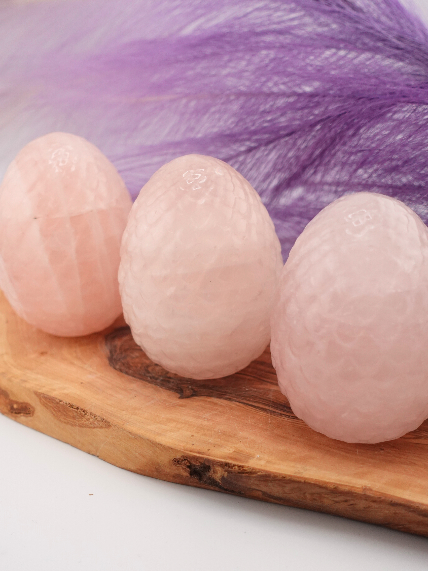 Three rose quartz dragon scaled eggs on a wooden display stand