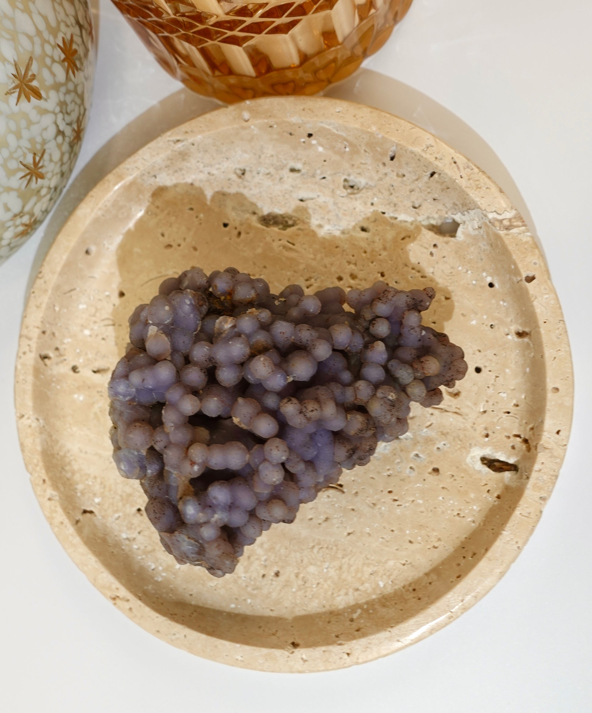 Grape Agate freeform specimen on decorative travertine dish with a white background.