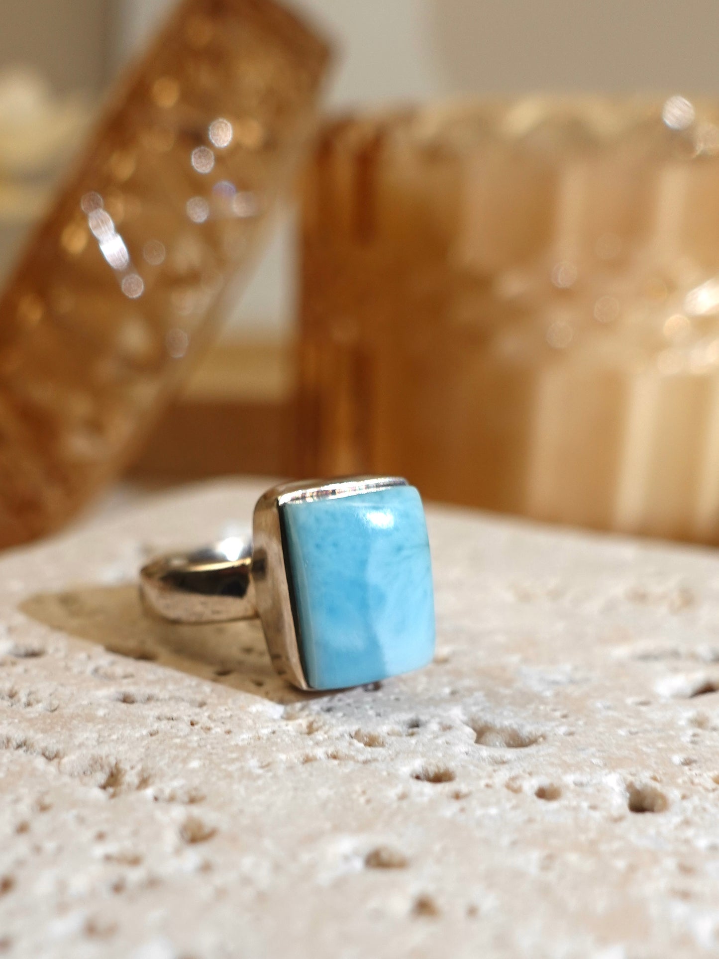 Larimar ring on travertine display with glass background