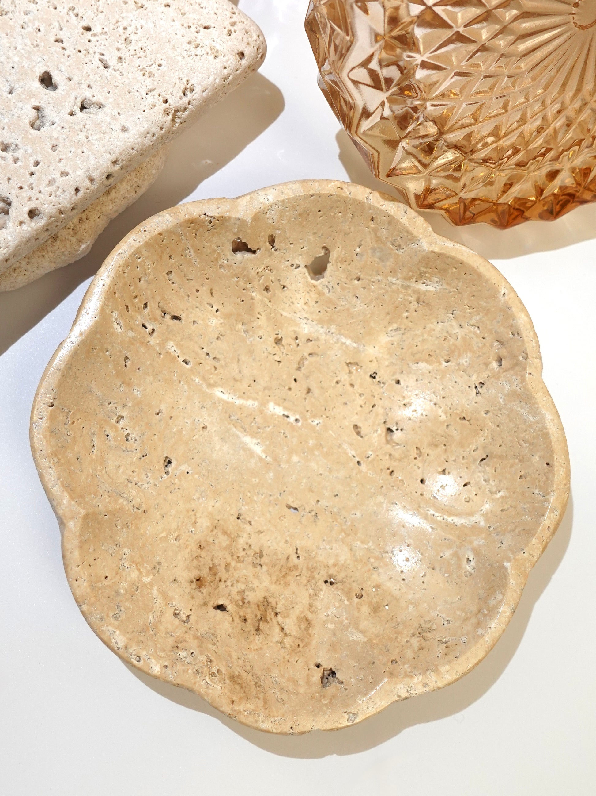 Travertine small scalloped dish with decorative pieces on white background.