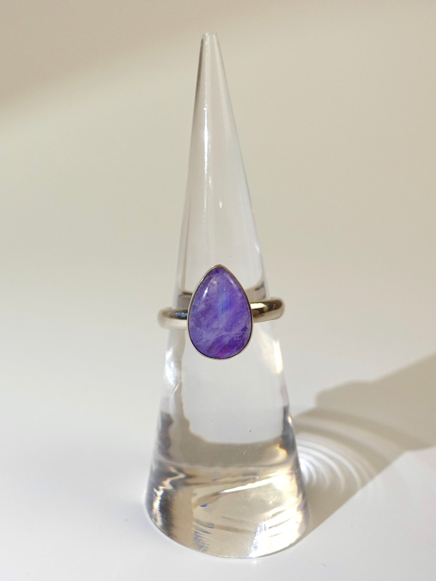 Ring with a purple moonstone stone on a cone-shaped stand against a white background