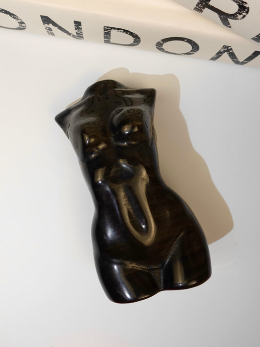 Gold sheen obsidian goddess body on white background with letttering in the background