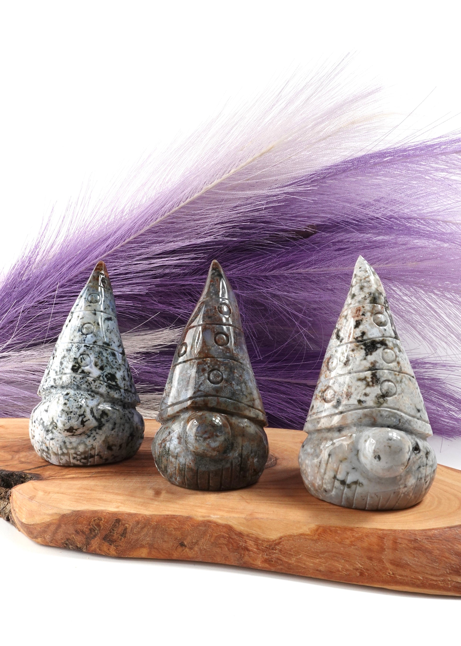 Three sea jasper gnomes on a wooden display stand