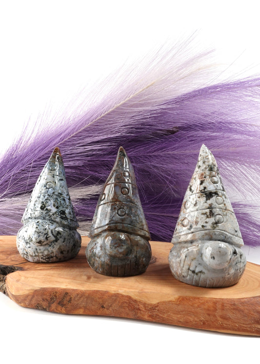 Three sea jasper gnomes on a wooden display stand