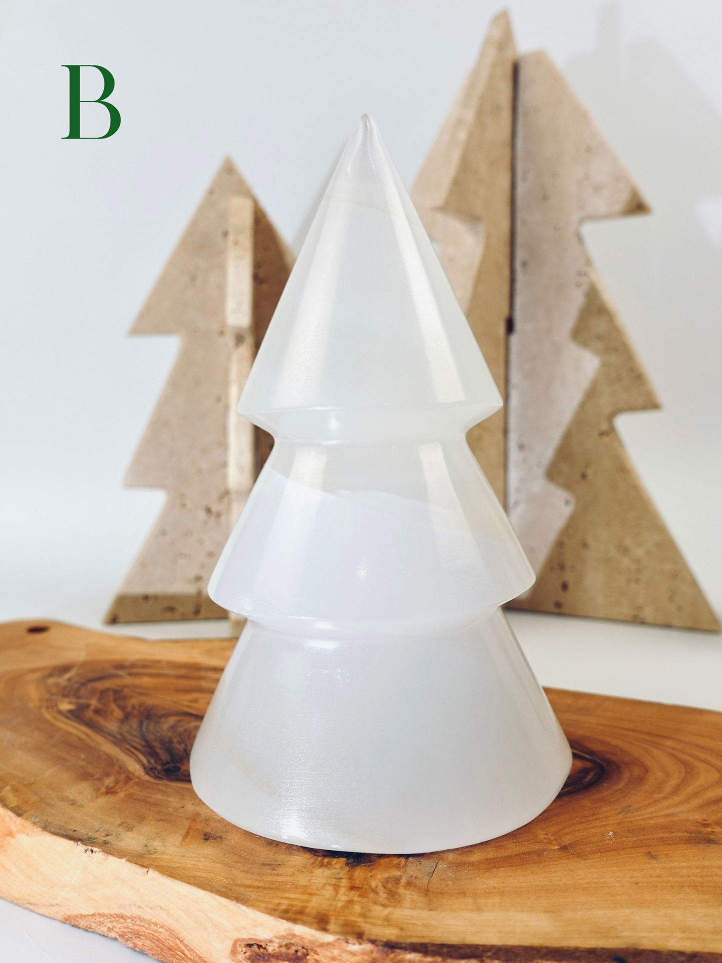White tree-shaped lamp on a wooden surface with wooden trees in the background