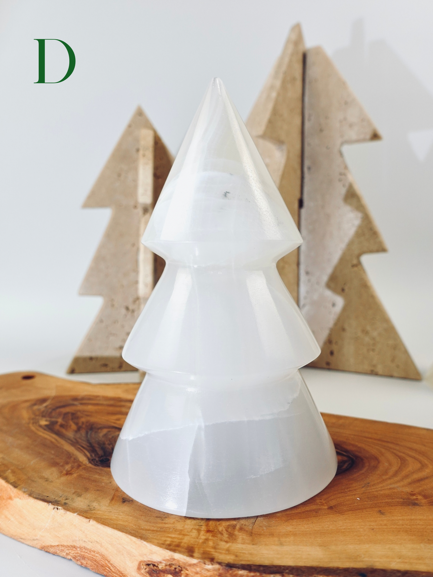 White ceramic Christmas tree on a wooden surface with wooden trees in the background
