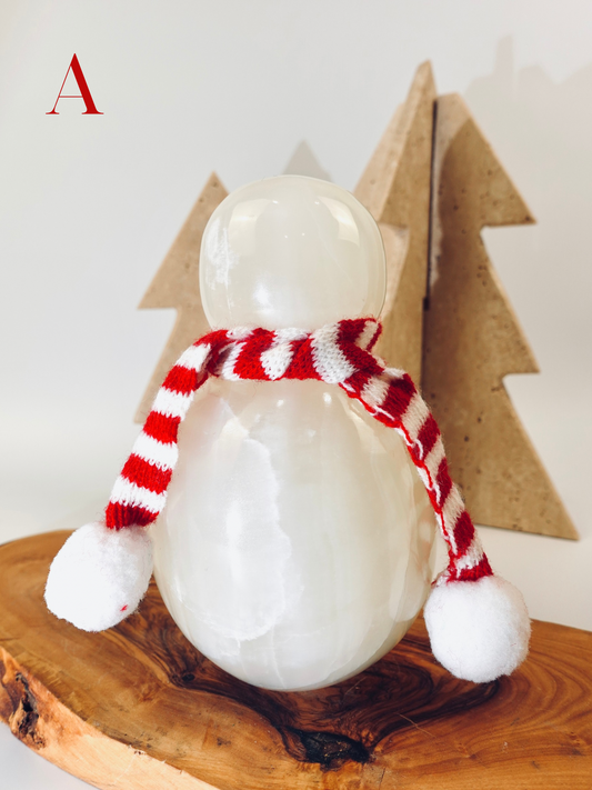 Decorative snowman figurine with a red and white striped scarf on a wooden surface.
