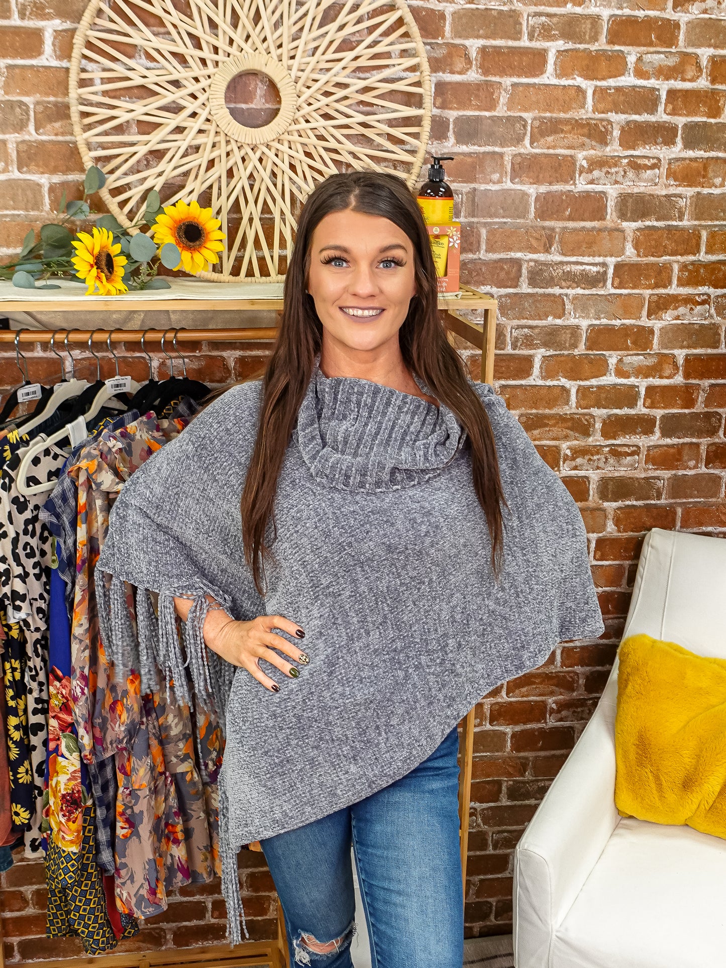 Grey knit poncho with fringe detail on one side.