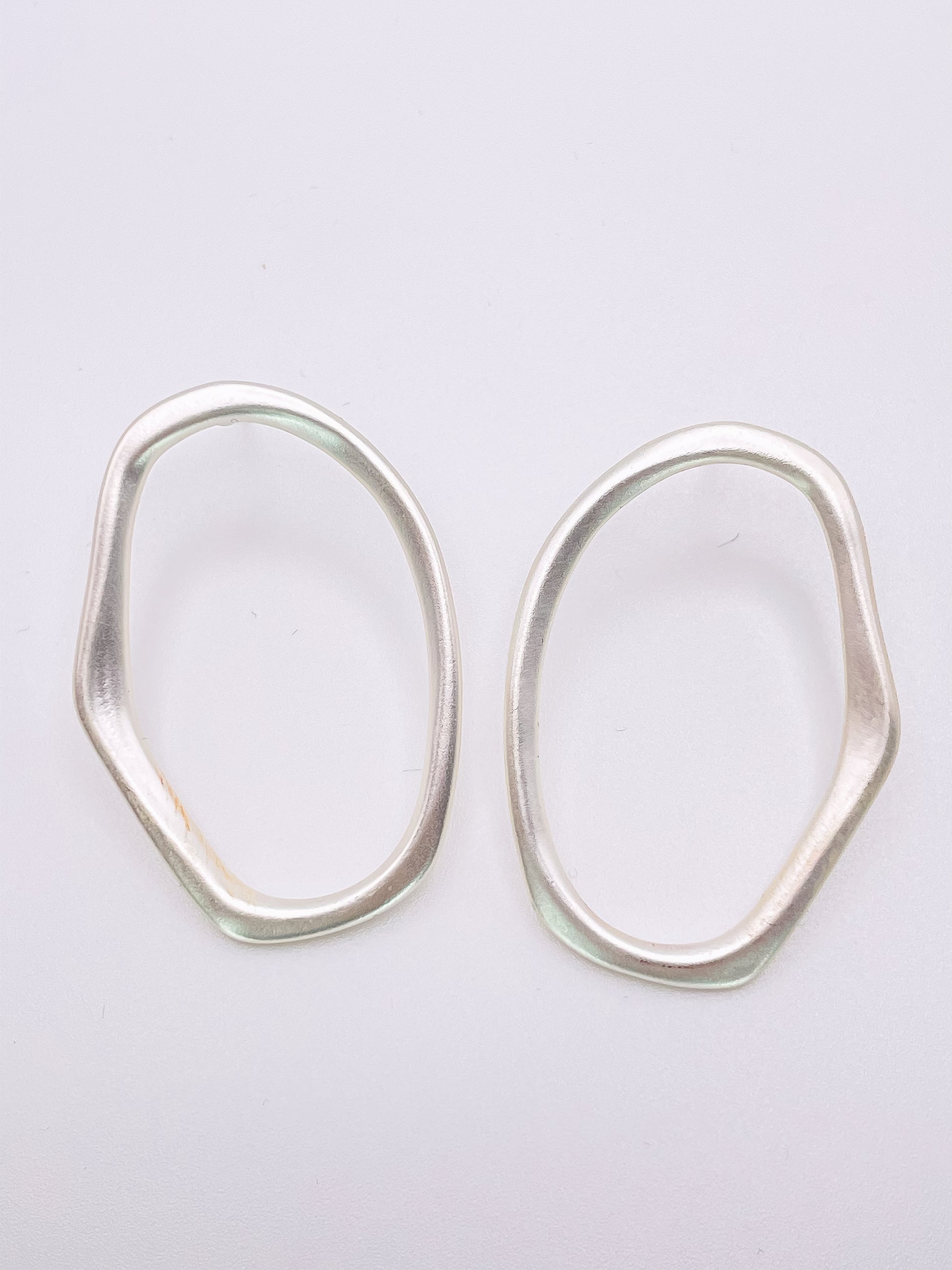 silver hoops that are imperfect oval hoops.