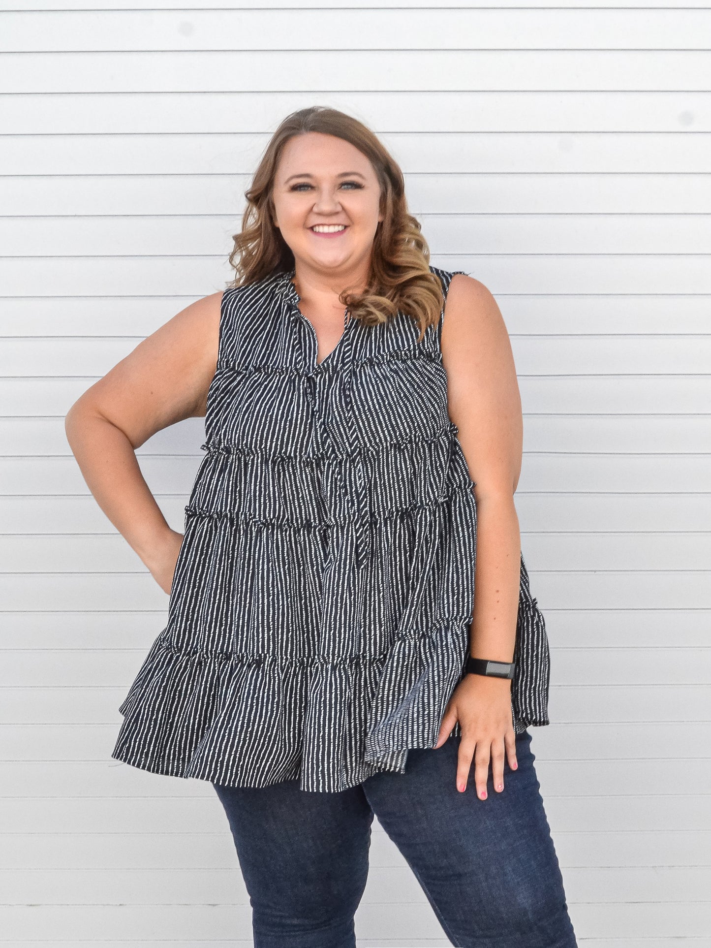 Black tiered striped sleeveless top with keyhole neckline.