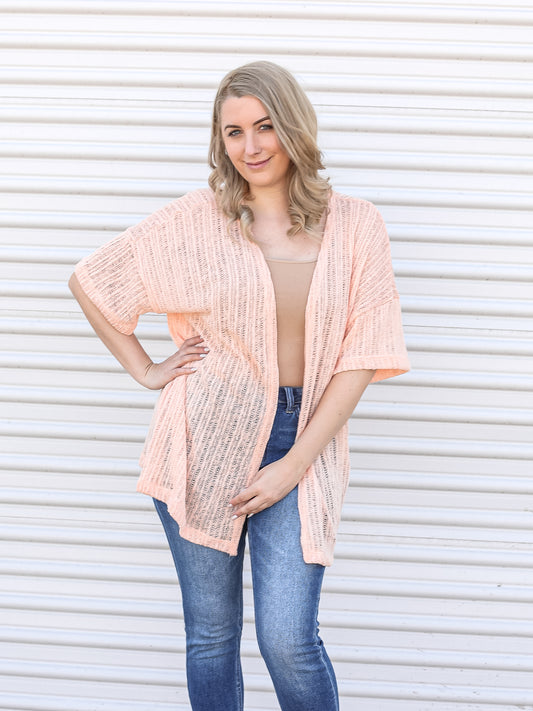 Light pink, short sleeve knit open cardigan styled with a tank top and denim. 
