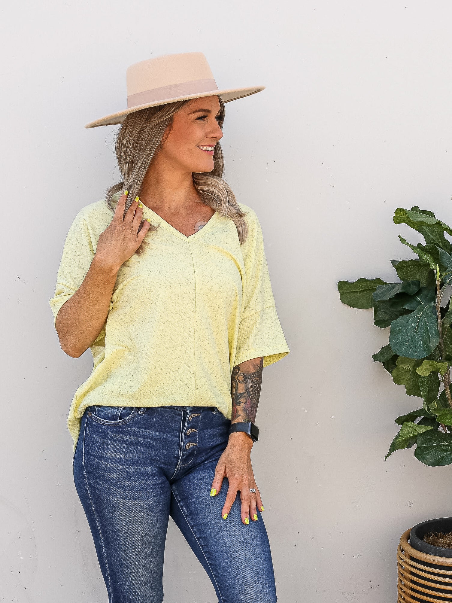Yellow heathered short sleeve, v-neck top. Styled with jeans and wide hat.