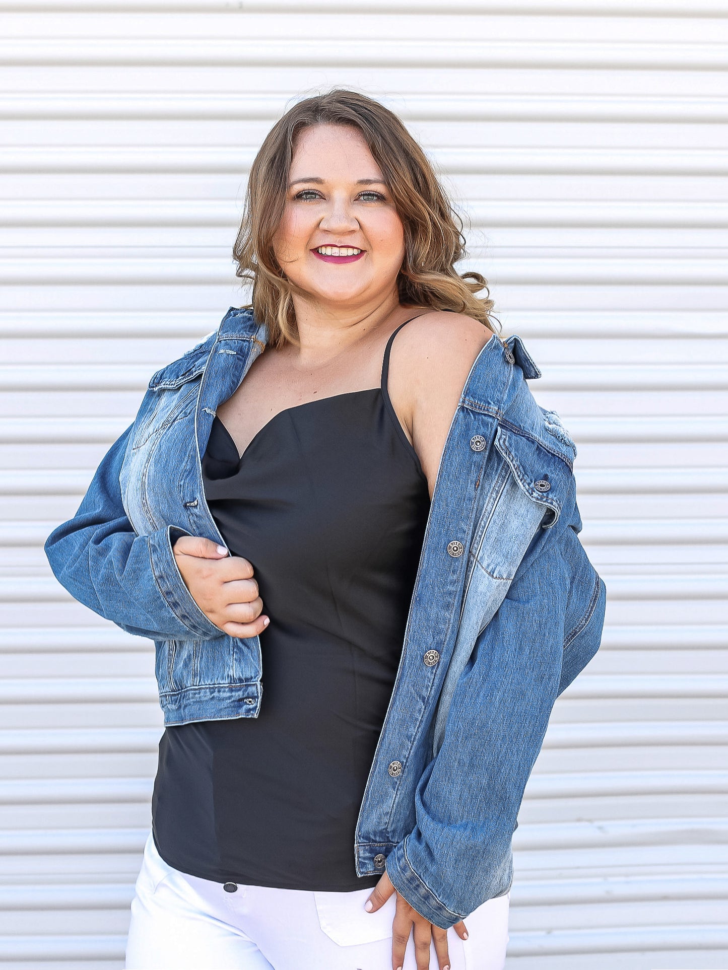 black tank peaking through denim jacket paired with white jeans