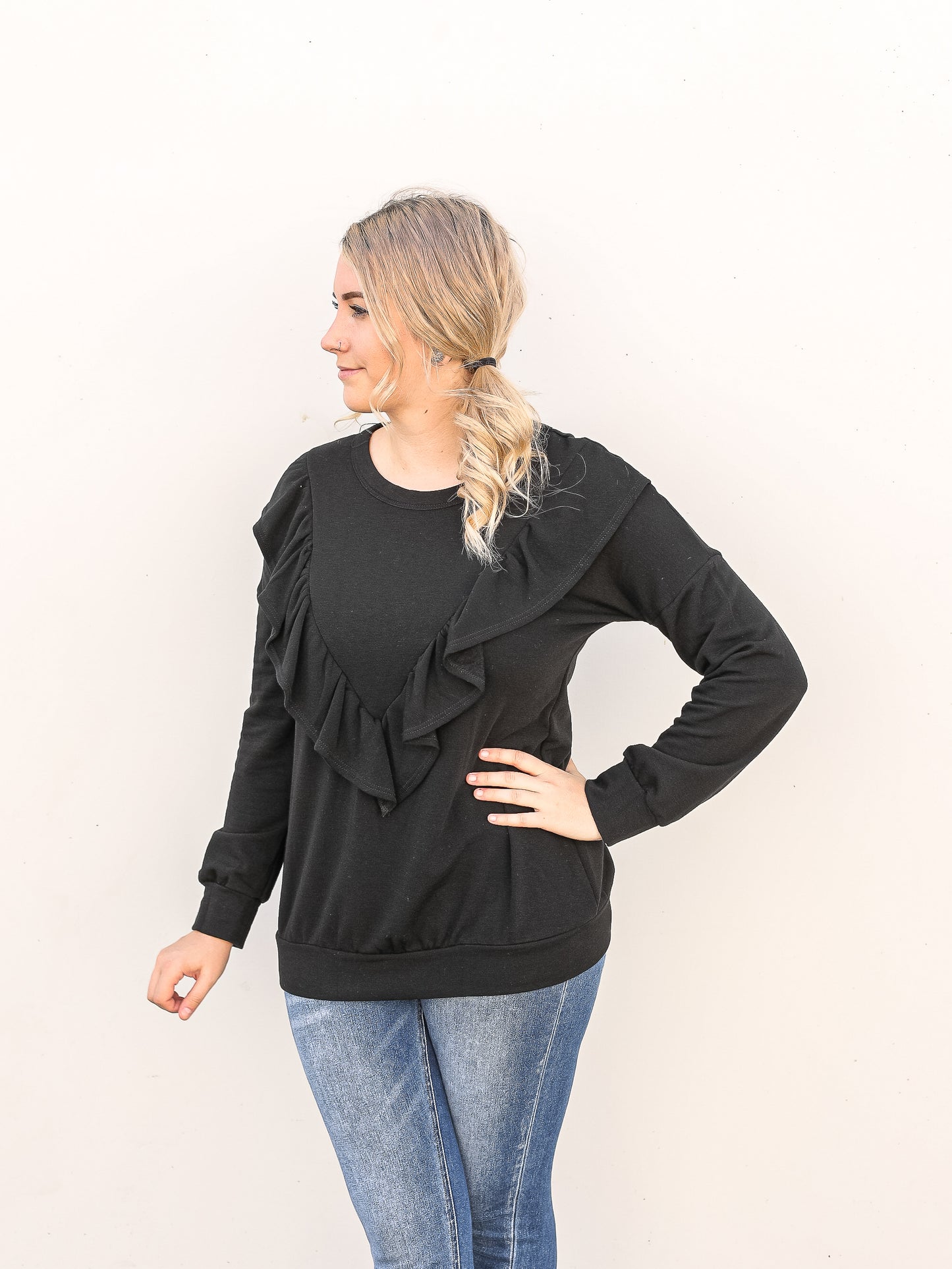 Ruffled black long sleeve top paired with jeans