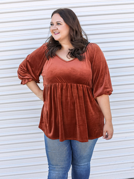 Rust colored babydoll style top paired with jeans