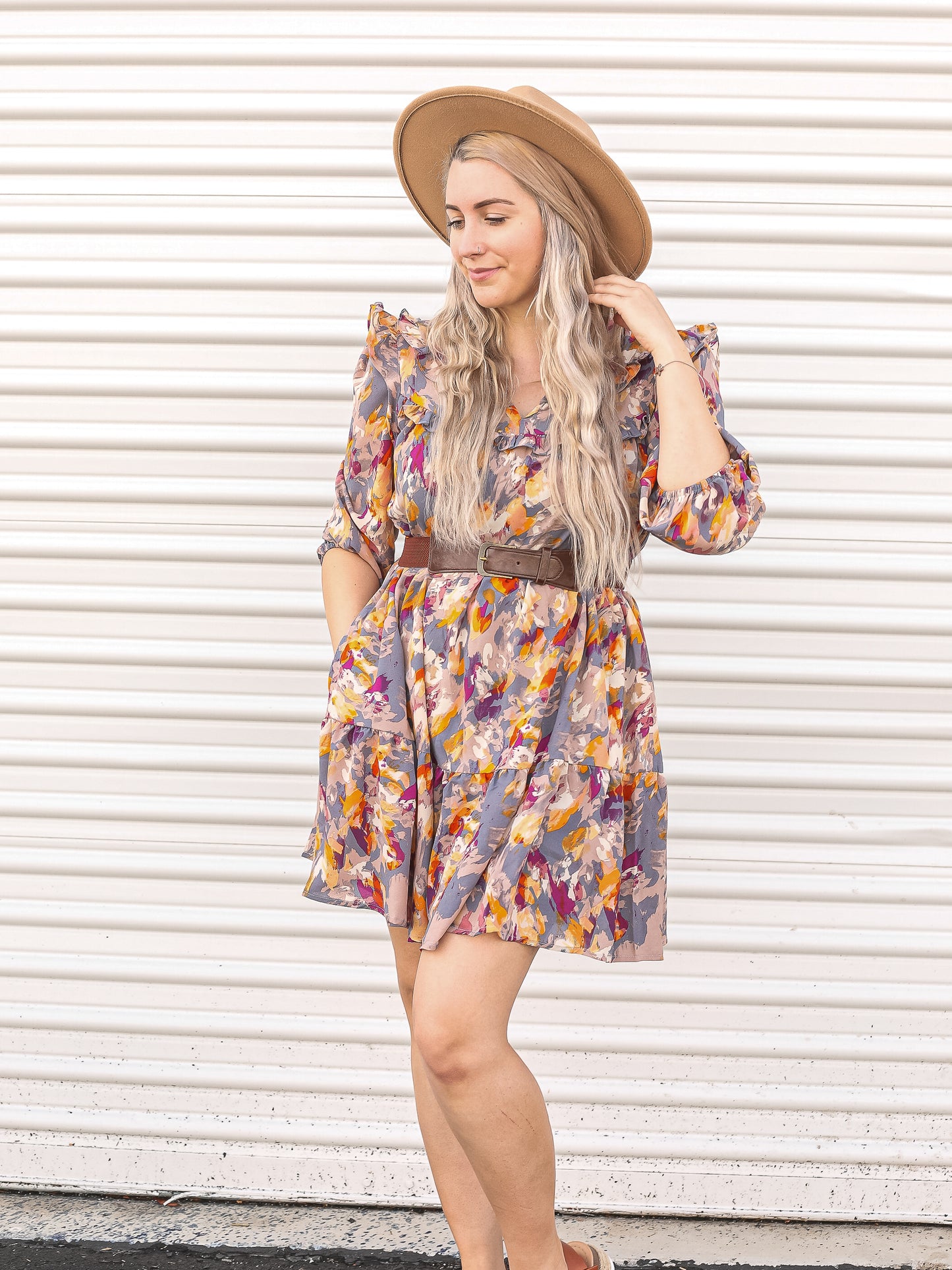 Multicolored dress styled with a belt and a wide hat.