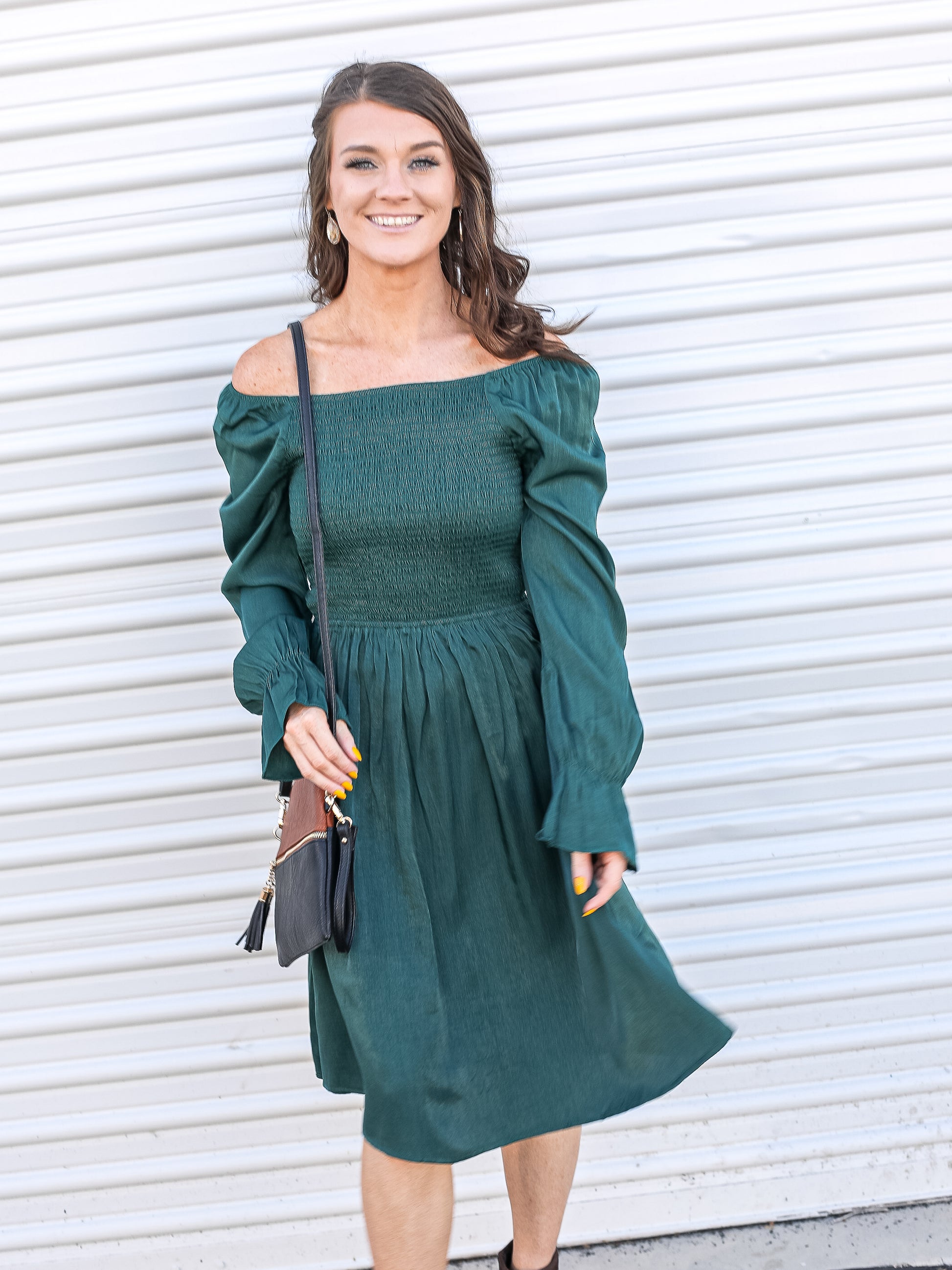 Emerald green dress off the shoulder paired with a classic crossbody purse