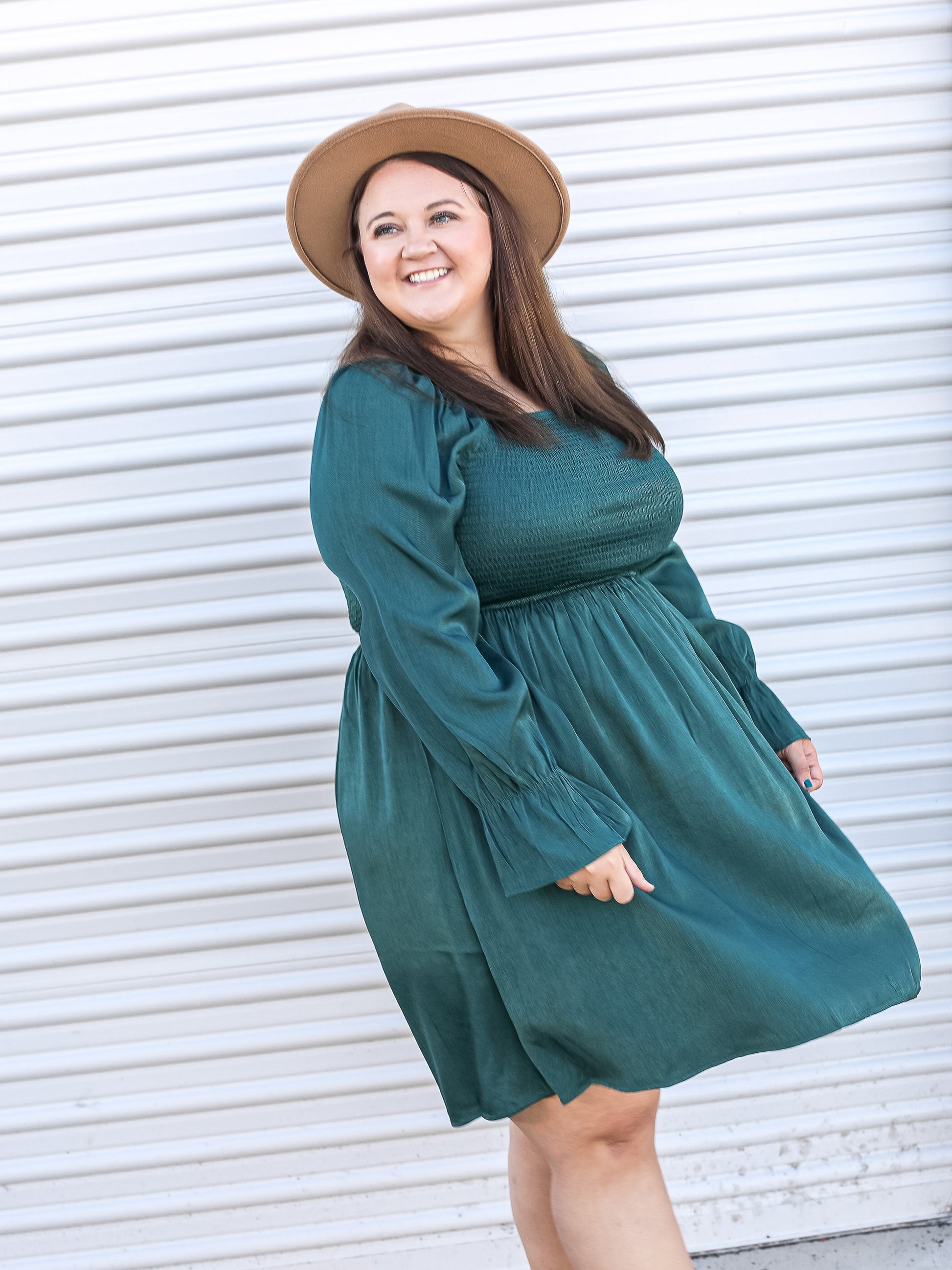 twirling in an emerald green dress styled with a wide brimmed hat.