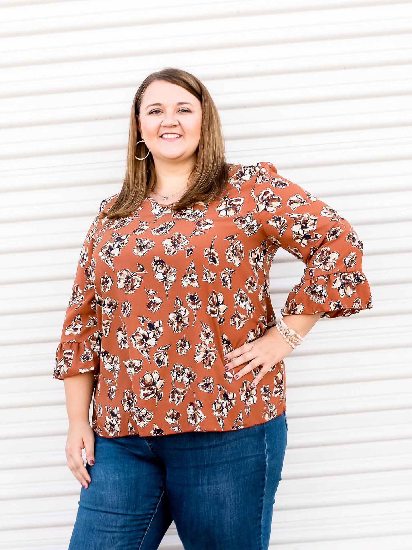 Rust colored blouse with 3/4 sleeves and floral pattern throughout.