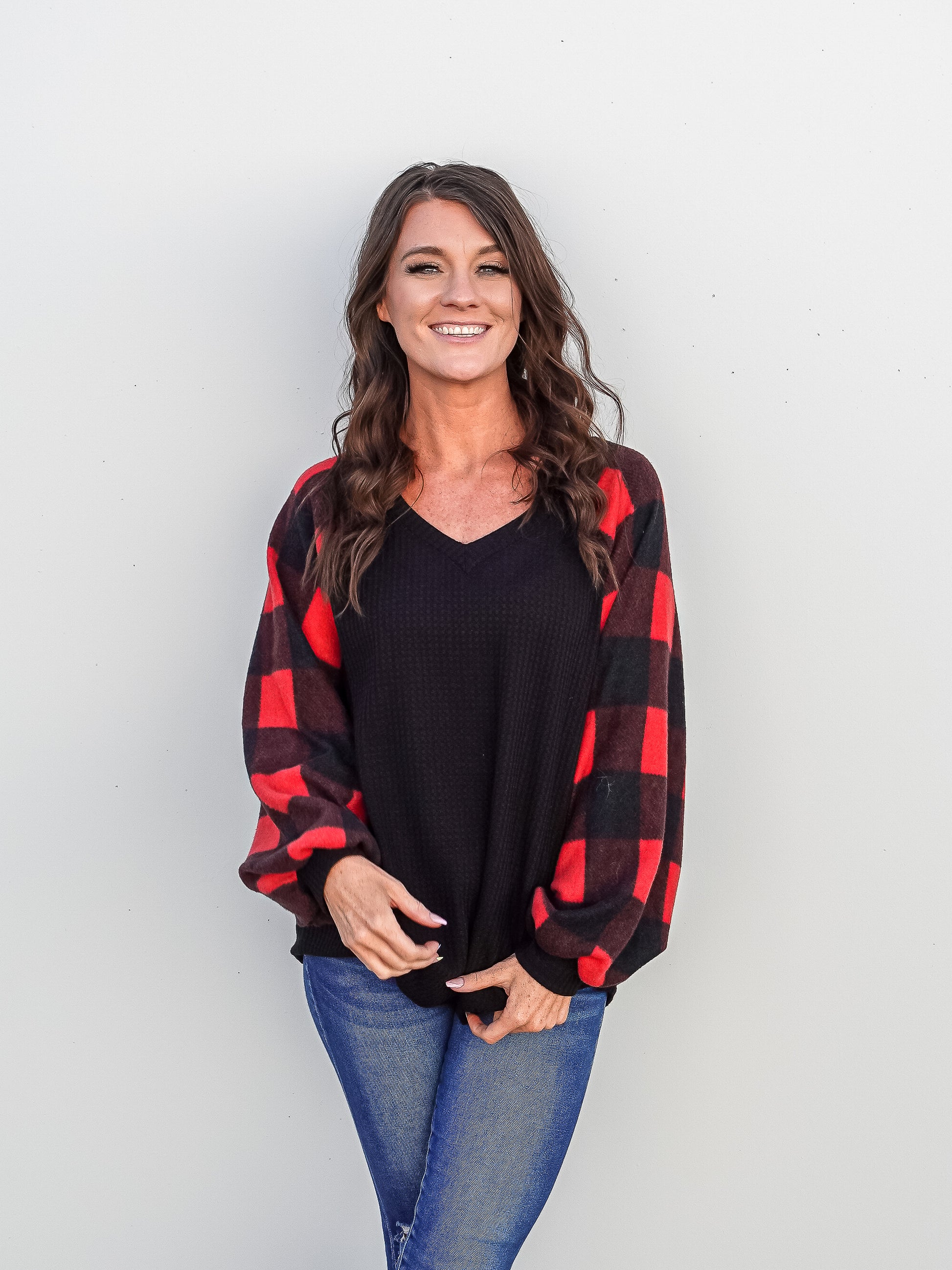 Black waffle knit top with long balloon sleeves that are buffalo plaid.