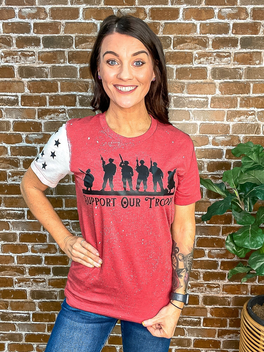 Red tee with "Support Our Troops" on the front and one white sleeve with stars. 
