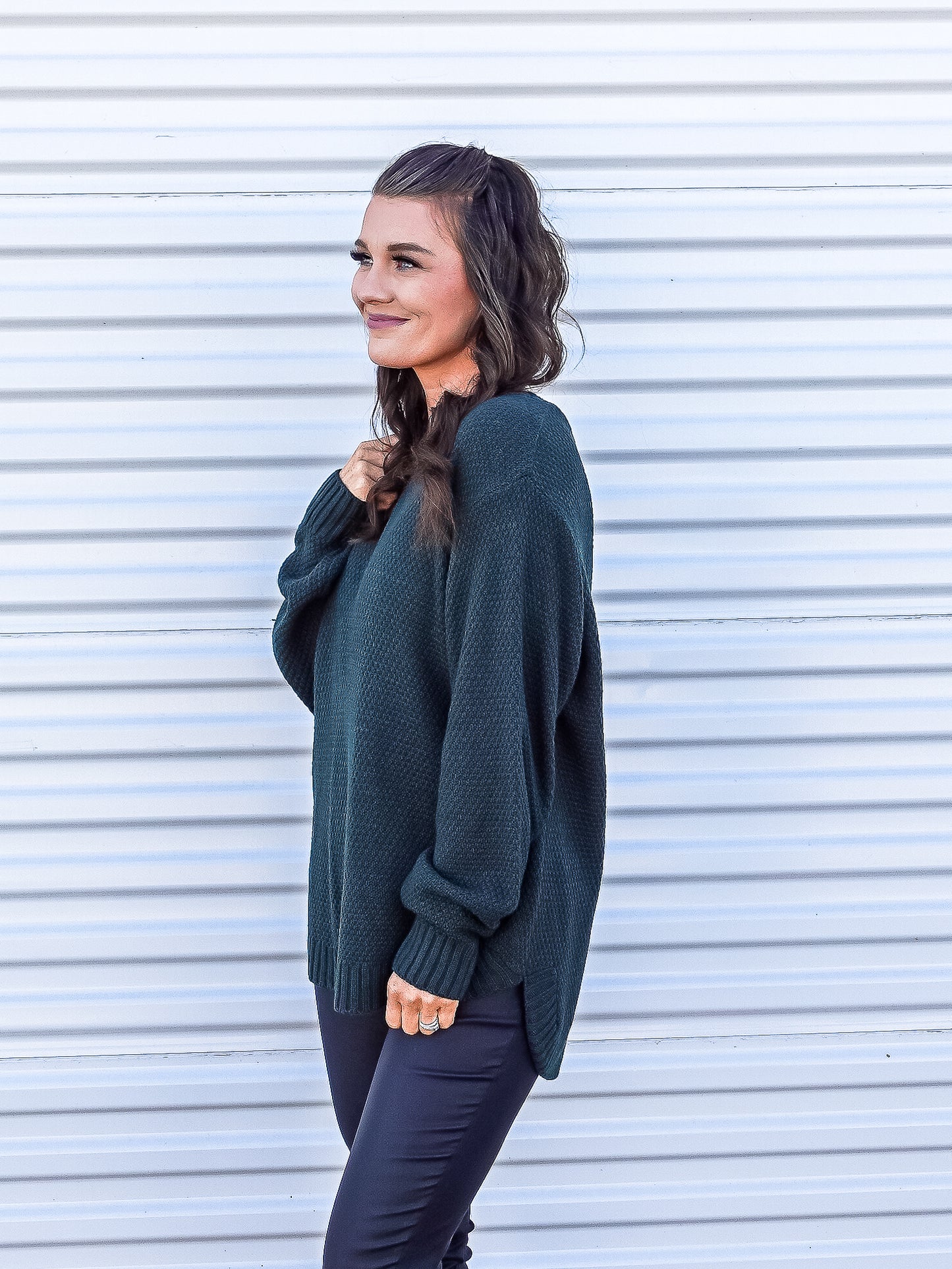 Side view of green classic high low sweater. 