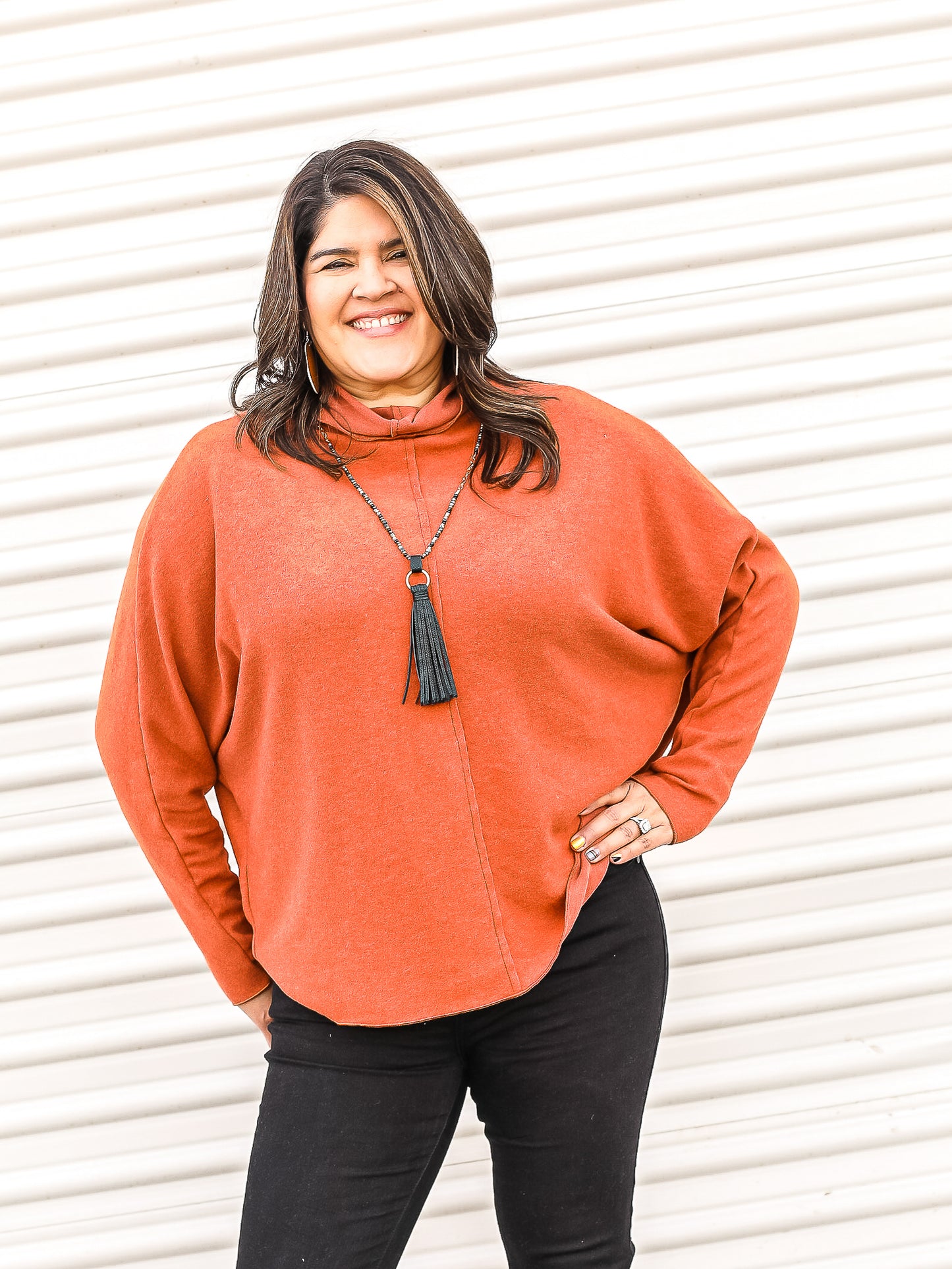 Orange dolman sweater with cowl neck styled with black jeans.
