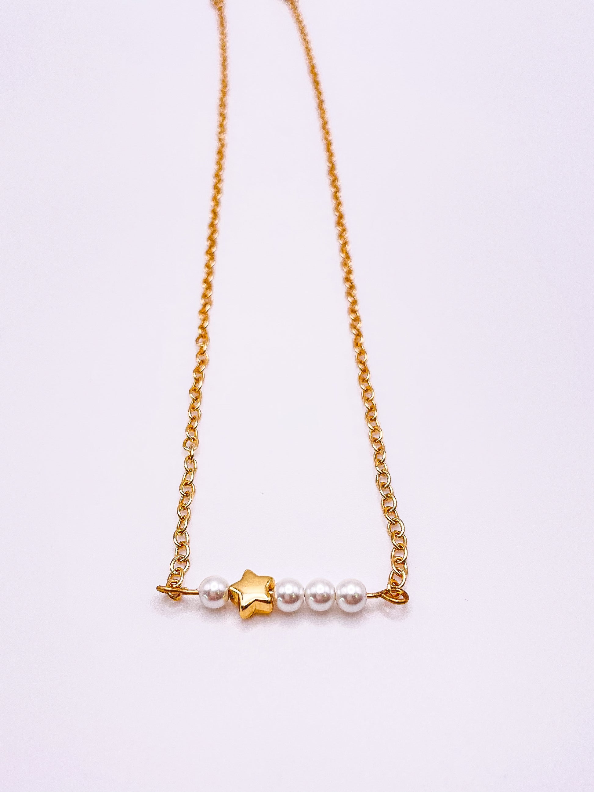 Gold necklace with little star and pearls.