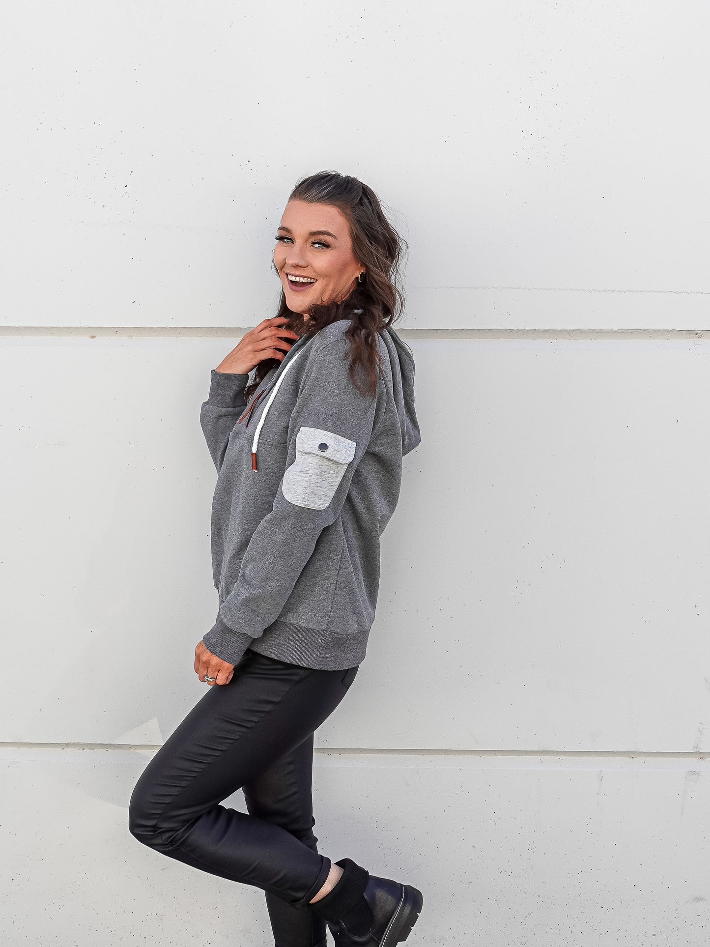 Side view of grey pull over with view of elbow pocket with button.