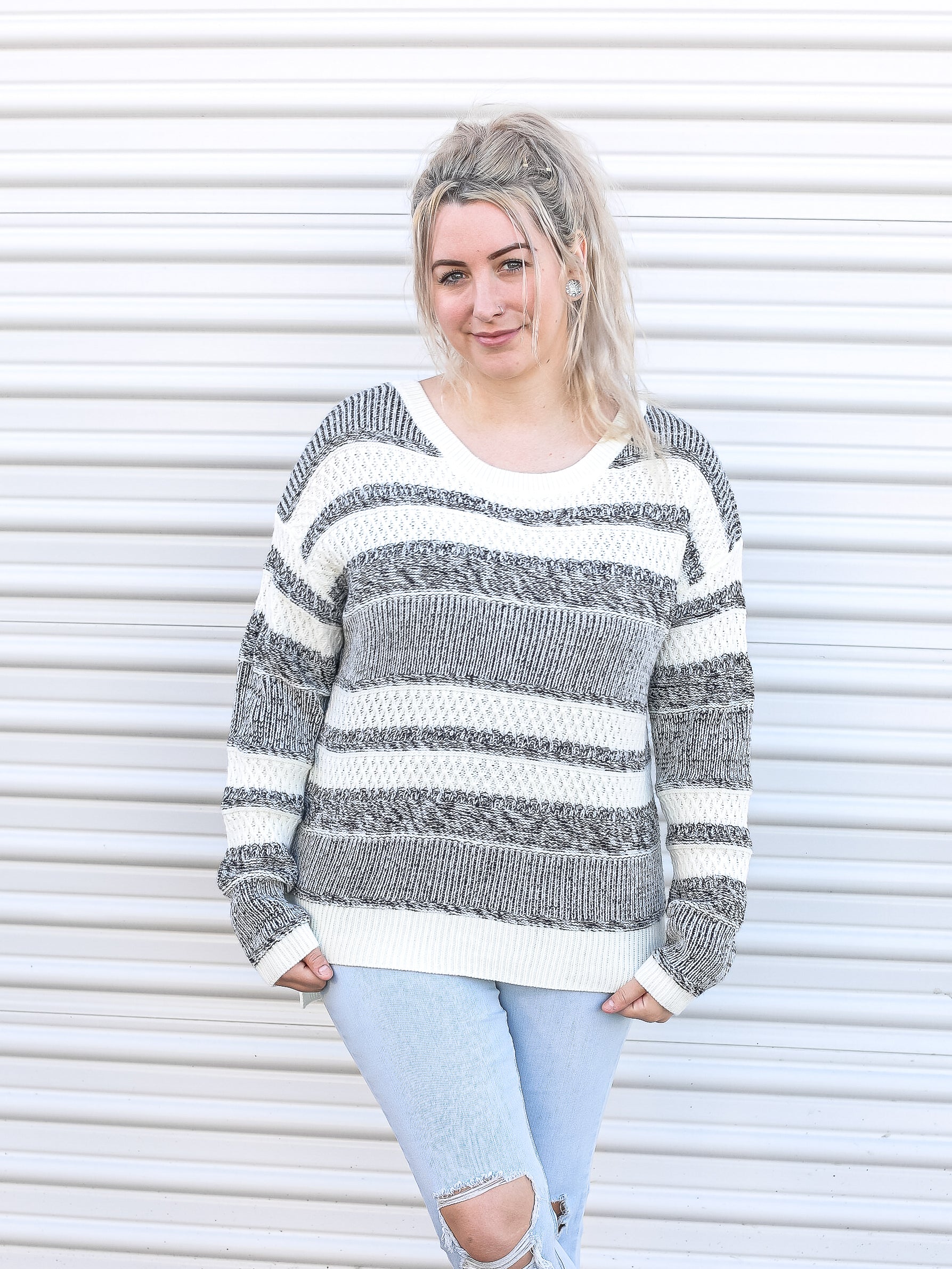 White sweater with black/grey horizontal stripes in various thicknesses. 