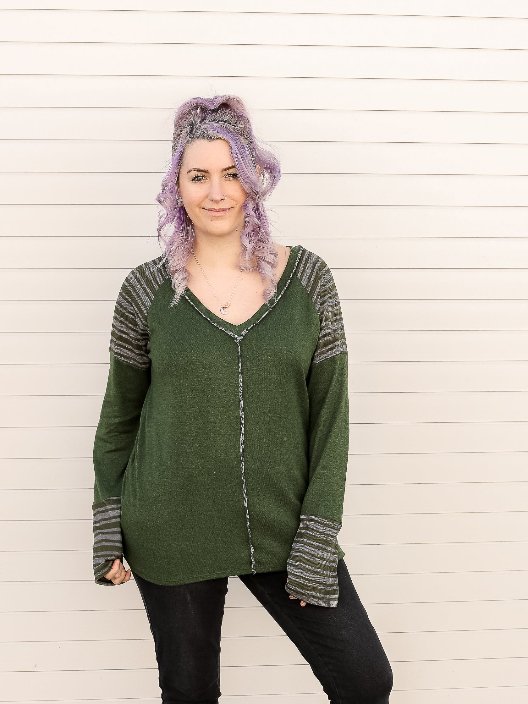 Green long sleeve top with grey various sized stripes on the shoulders and wrists. 