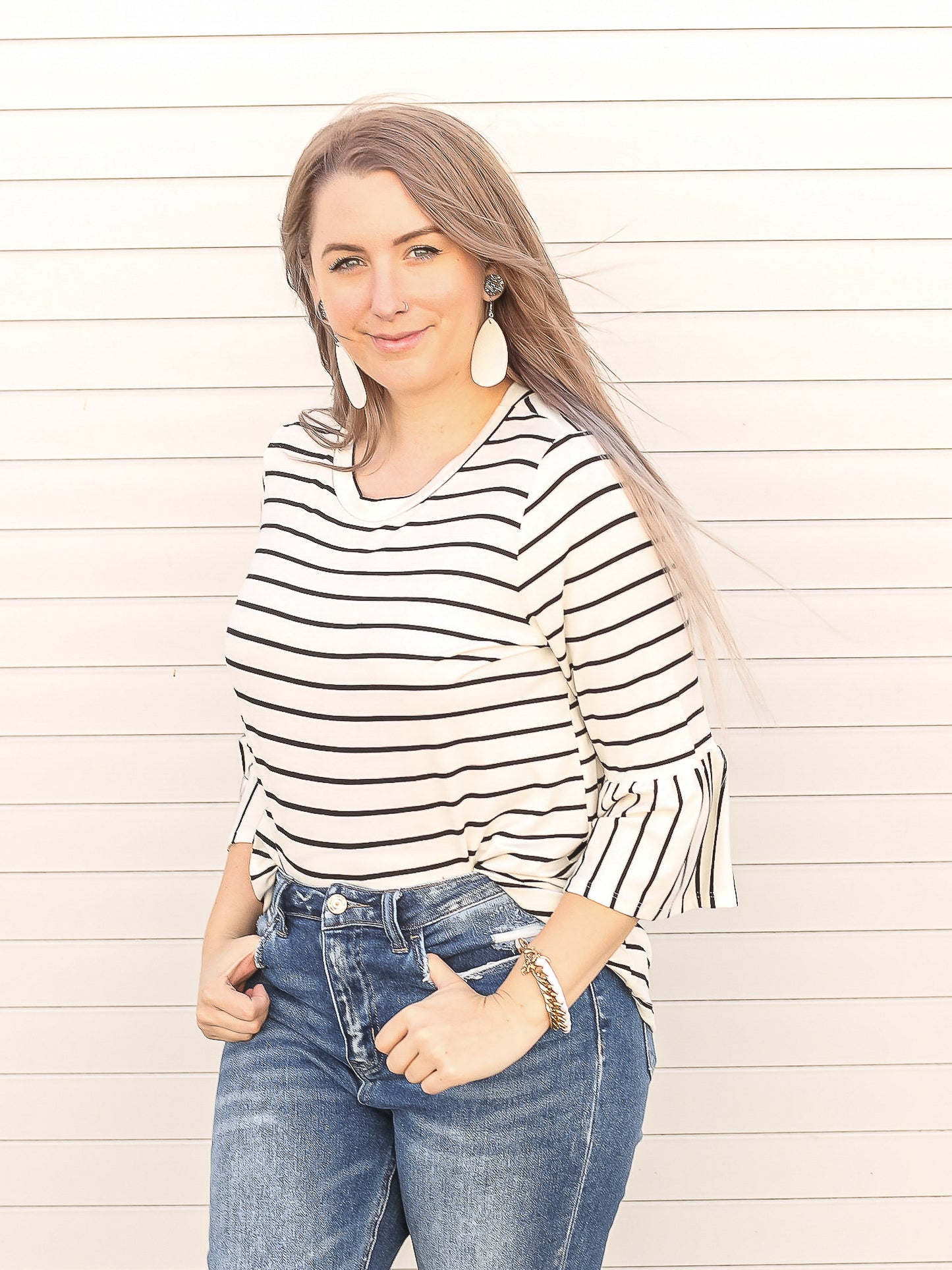 Simple white and black striped 3/4 sleeve top tucked into denim