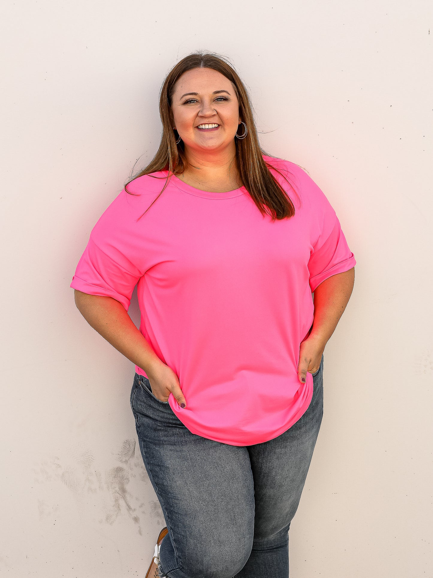 Neon pink short sleeve top with rounded neckline and cuffed short sleeves