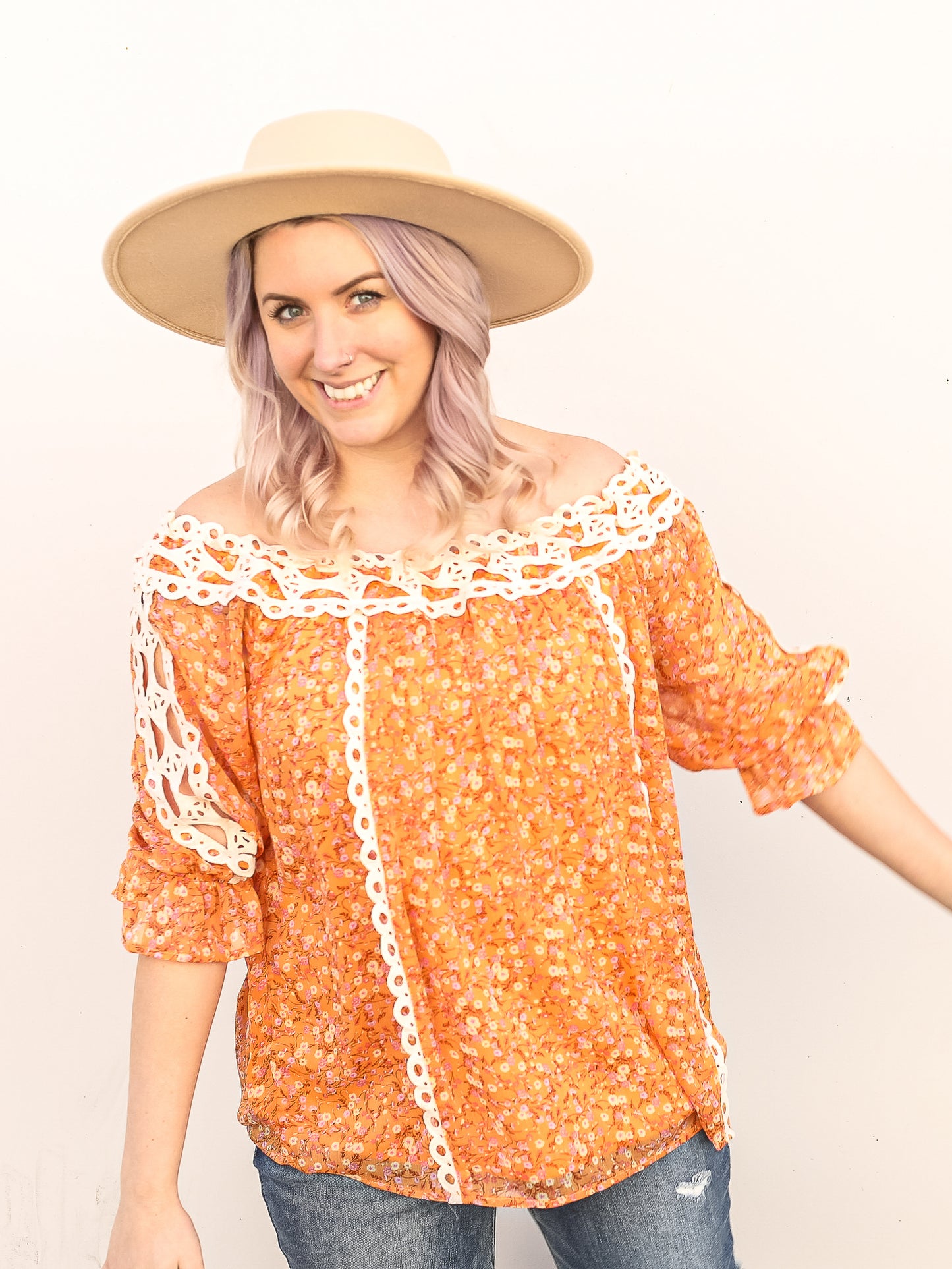 Orange floral top paired with a hat and jeans