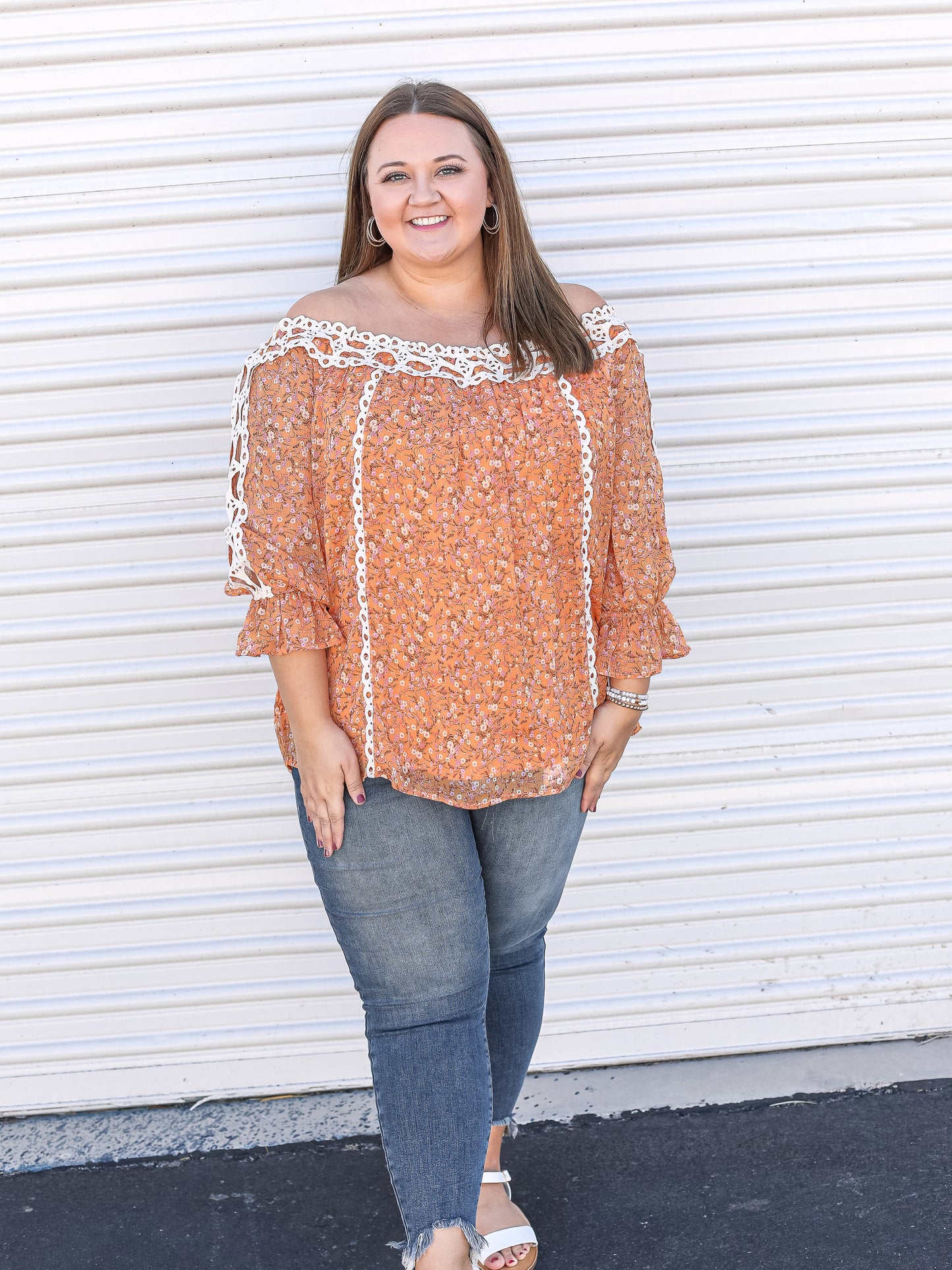 orange floral top paired with jeans and sandals. 