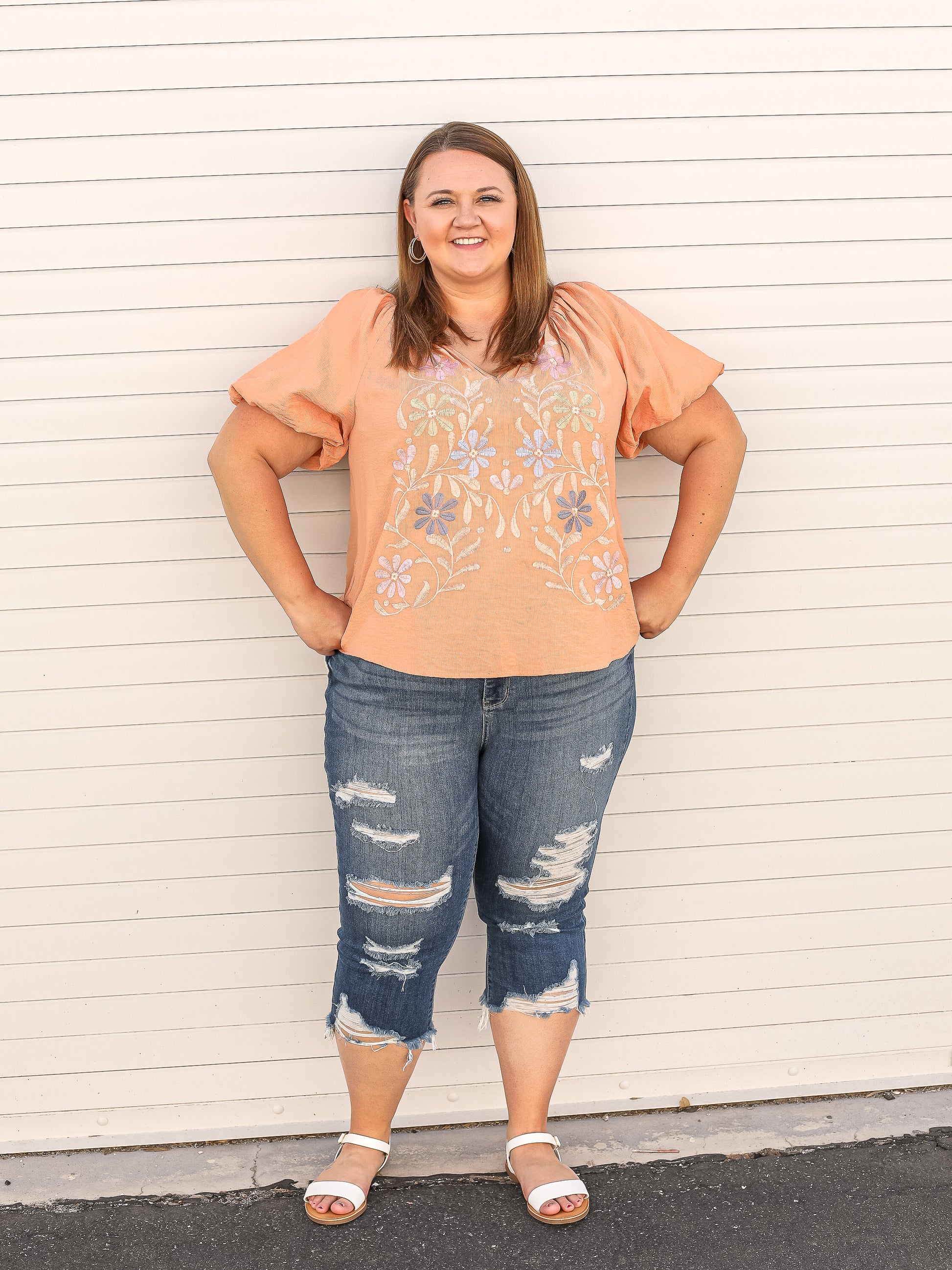 Apricot colored blouse with floral embroidered details on the front.