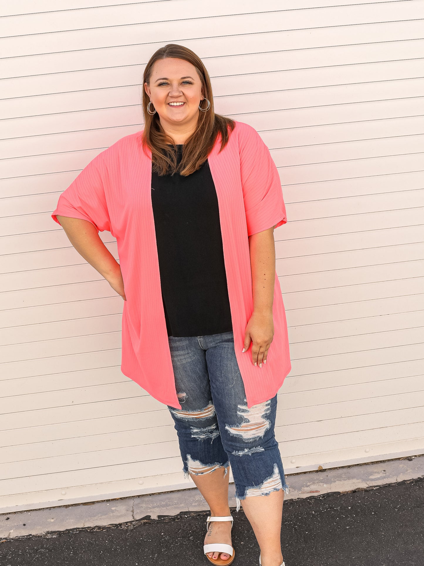 Open front cardigan with ribbed details and short sleeves in neon pink. Styled with capris and a black top.
