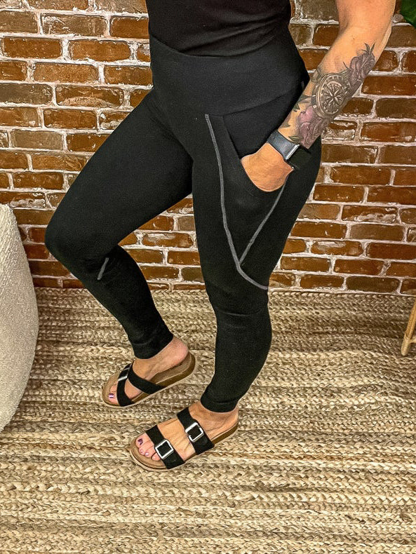 Side view of black leggings with grey stitched detail.